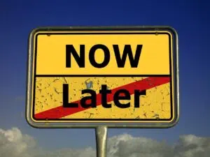 Procrastination thoughts. A yellow street sign with "NOW" at the top and "Later" crossed out with a red slash at the bottom, against a blue sky with clouds, representing a decision to take action immediately. Zip Codes: Austin area 78746, 78730, 78733, 78739, 78732, 78701, 78703. Round Rock area 78681, 78665, 78641, 78717, 78613.