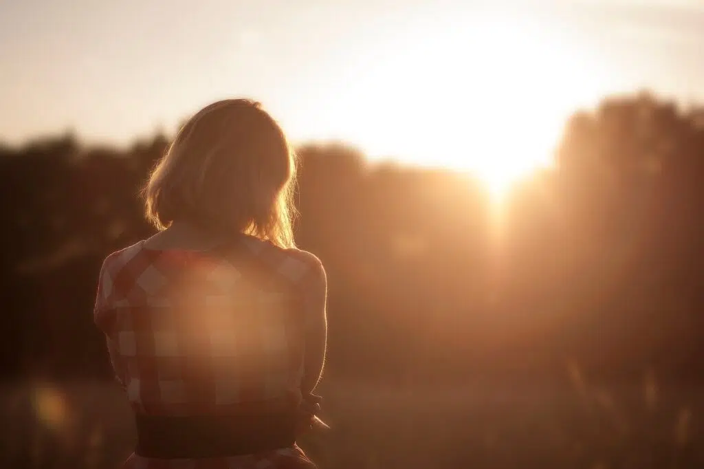 Woman in a park at dusk, hand on heart, taking a calming breath after a friendship breakup. Zip Codes: Austin area 78746, 78730, 78733, 78739, 78732, 78701, 78703. Round Rock area 78681, 78665, 78641, 78717, 78613.